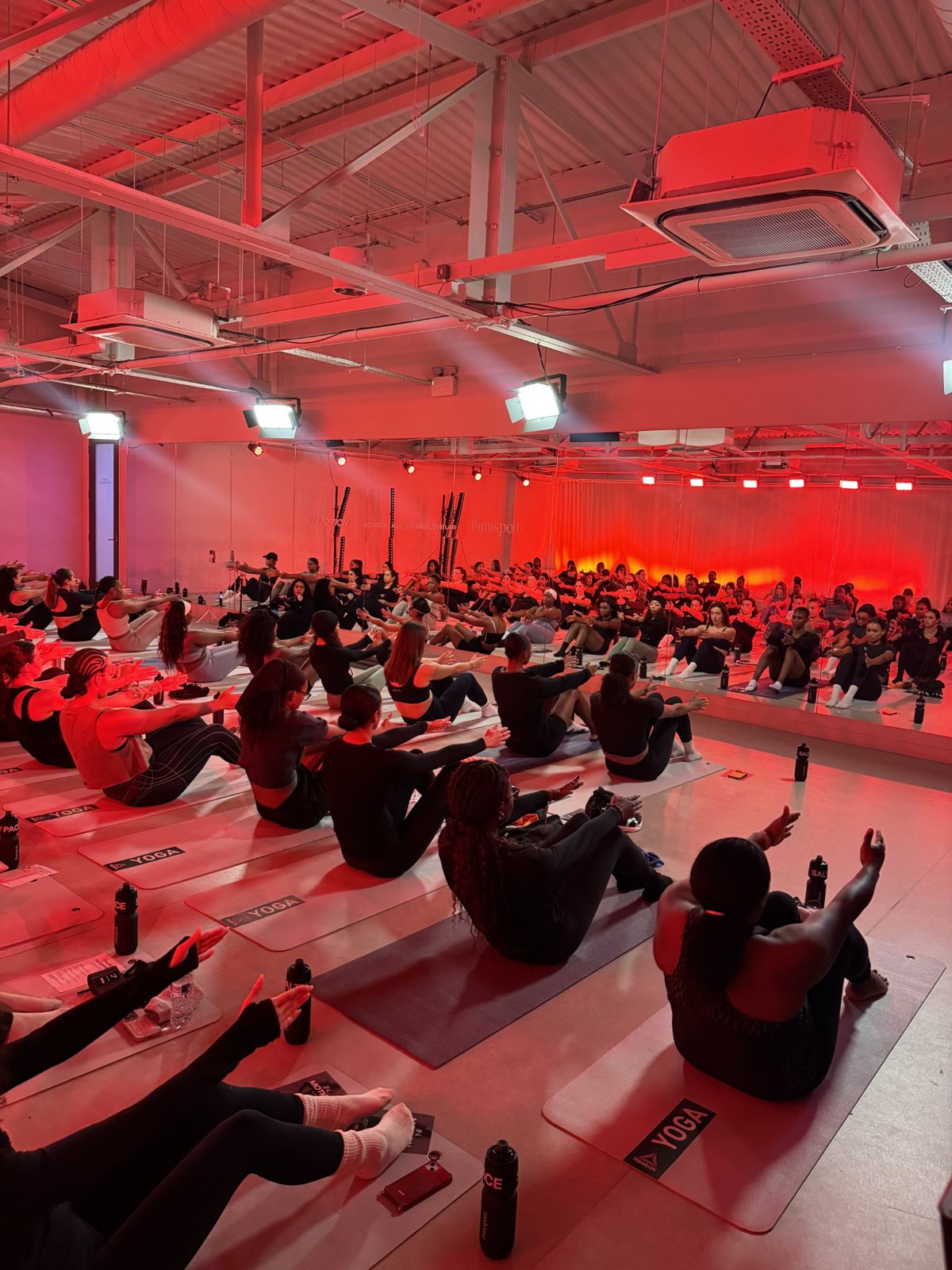 A group studio class stretching on yoga mats under red lighting at Wellness Days